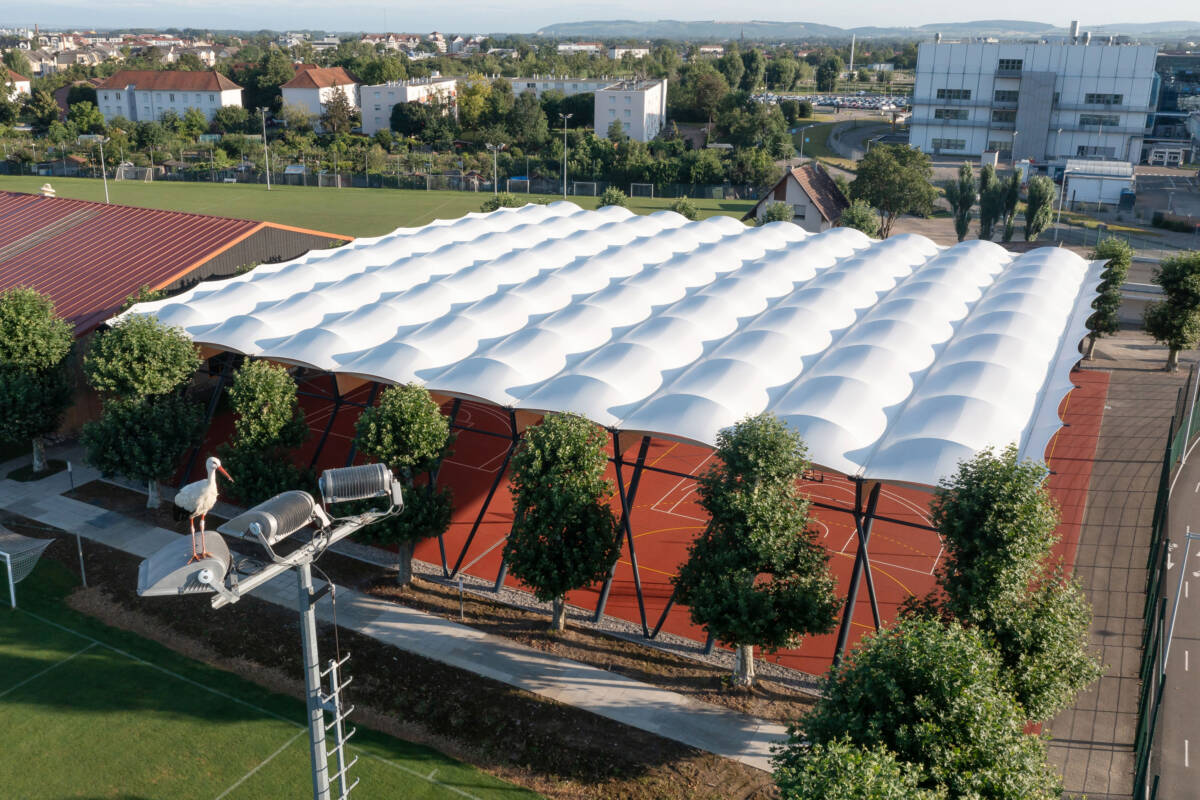 SMC2 a construit d'un préau sportif multisport dans le Haut-Rhin avec couverture en membrane textile et charpente bois avec poteaux acier.