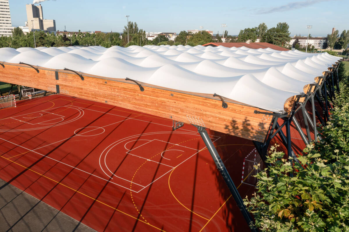 SMC2 a construit d'un préau sportif multisport dans le Haut-Rhin avec couverture en membrane textile et charpente bois avec poteaux acier.
