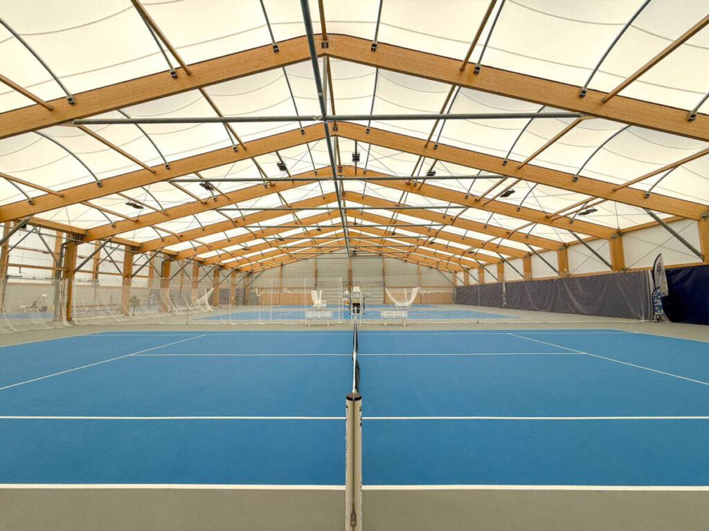 SMC2 a conçu et construit une halle sportive à Trélissac avec 4 courts de tennis et 2 de padel, alliant bois, acier et membrane textile.