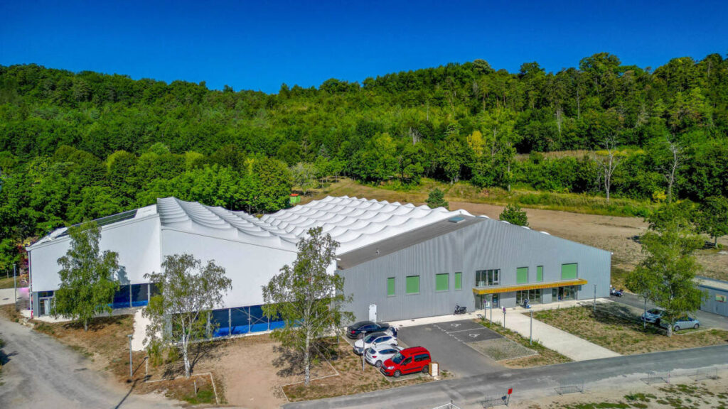 SMC2 a conçu et construit une halle sportive à Trélissac avec 4 courts de tennis et 2 de padel, alliant bois, acier et membrane textile.