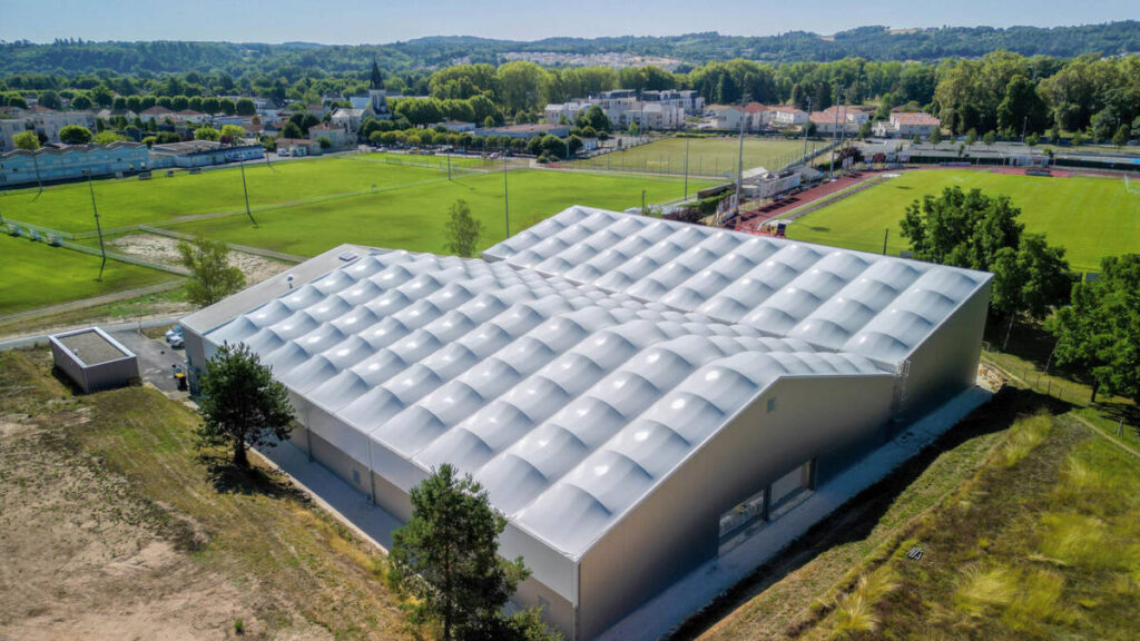SMC2 a conçu et construit une halle sportive à Trélissac avec 4 courts de tennis et 2 de padel, alliant bois, acier et membrane textile.