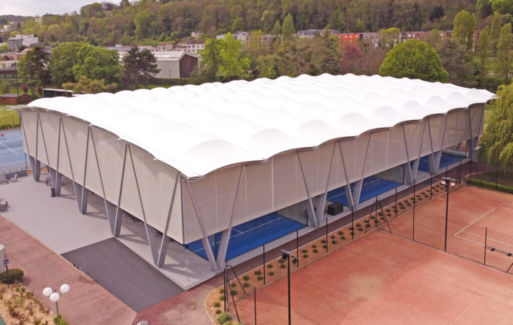 SMC2 a couvert 5 terrains de padel au club Les Pyramides avec une structure bois-acier grise et une membrane textile élégante et durable.