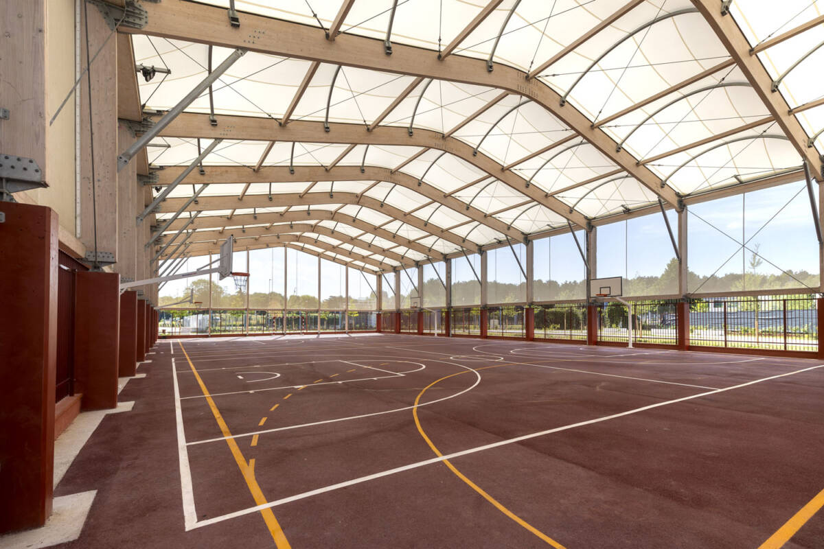 Construction d’un préosport de 2 000 m² au collège de Bobigny : structure bois-acier, couverture textile, façades micro-perforées et clôtures basses.