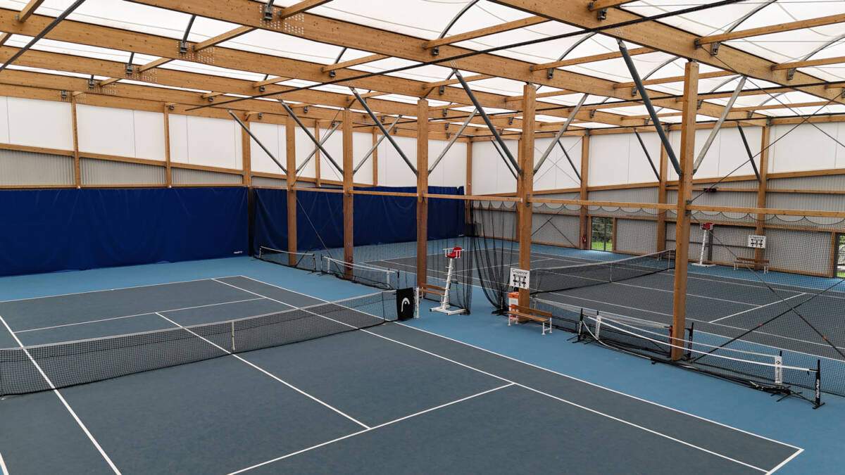 Construction d’un tennis couvert de 1400 m² : charpente bois lamellé-collé, membrane textile et sol sportif performant.