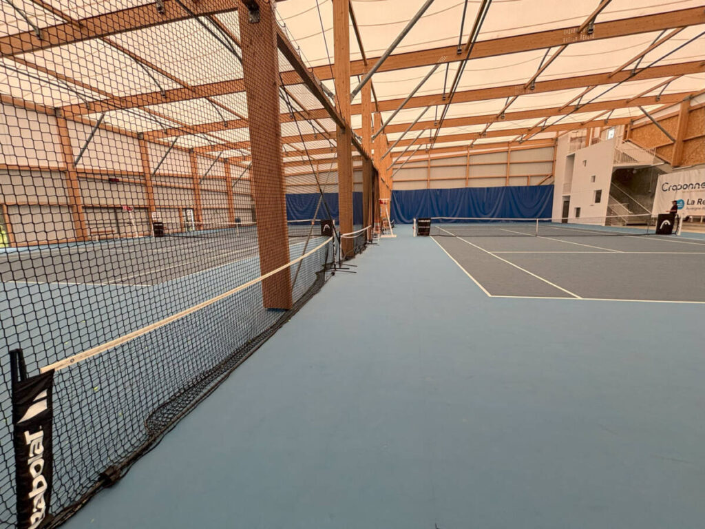 Construction d’un tennis couvert de 1400 m² : charpente bois lamellé-collé, membrane textile et sol sportif performant.