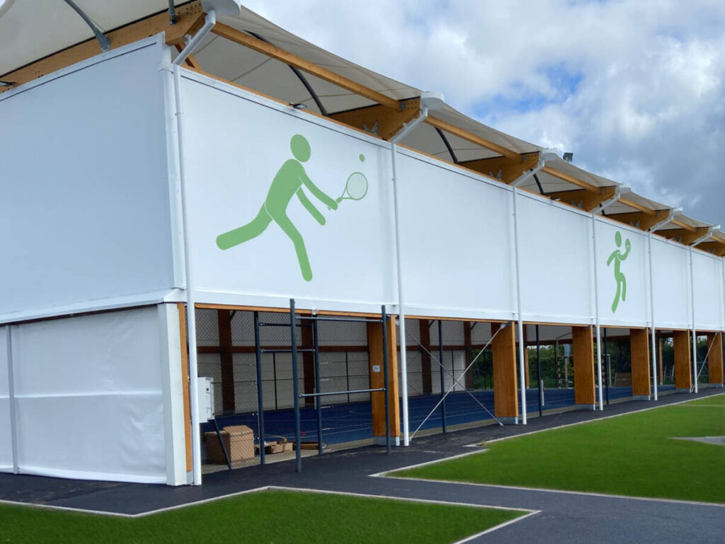 Découvrez le nouveau préau multisport de 908 m² à Quettreville-sur-Sienne, alliant membrane textile, charpente mixte et équipements modernes.