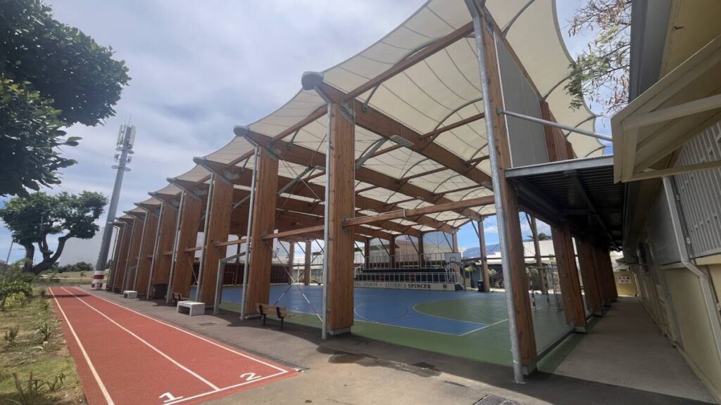 Halle sportive à Joinville (974) : structure bois lamellé-collé et membrane textile, conçue pour résister au climat tropical de La Réunion.