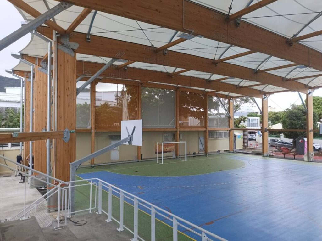 Halle sportive à Joinville (974) : structure bois lamellé-collé et membrane textile, conçue pour résister au climat tropical de La Réunion.